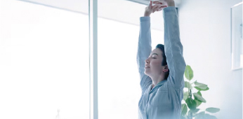 リビングでリラックスして両手を伸ばす女性